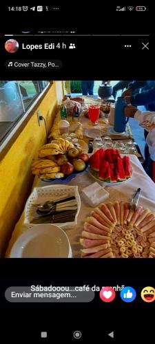 a long table with plates of food and fruit on it at Pousada do Juninho in Capitólio