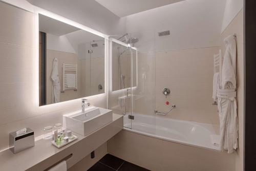 a white bathroom with a sink and a shower at NH Collection Milano Touring in Milan