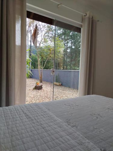 a bedroom with a bed and a large window at Suítes Garden in Pomerode
