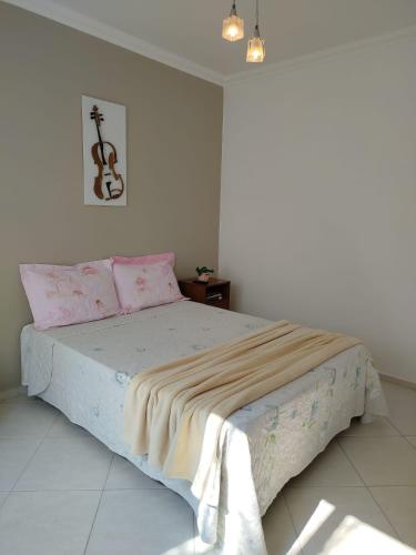 a white bedroom with a bed with pink sheets at Suítes Garden in Pomerode