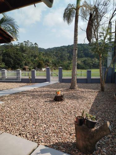 a gravel yard with two palm trees and a fence at Suítes Garden in Pomerode