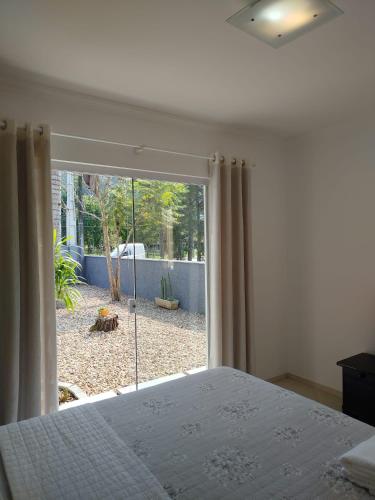 a bedroom with a bed and a large sliding glass door at Suítes Garden in Pomerode