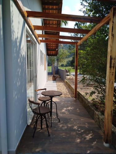 a patio with a table and chairs and a pergola at Suítes Garden in Pomerode
