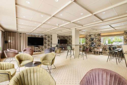 a lobby with chairs and tables and a flat screen tv at Kinsarvik Fjordhotel, BW Signature Collection in Kinsarvik