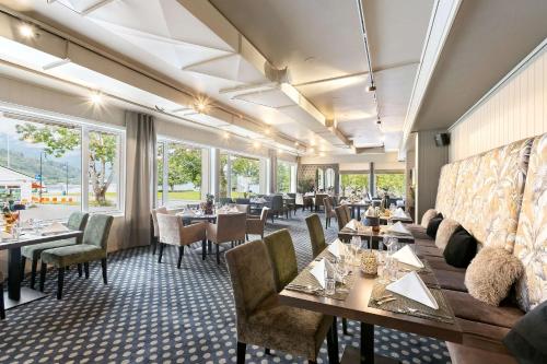 a restaurant with tables and chairs and windows at Kinsarvik Fjordhotel, BW Signature Collection in Kinsarvik