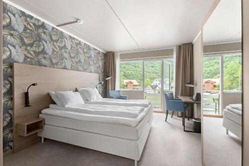 a hotel room with a bed and a desk and window at Kinsarvik Fjordhotel, BW Signature Collection in Kinsarvik