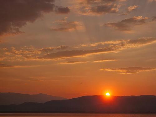 a sunset over the mountains with the sun in the sky at Lake Dream 1 in Sretenovo