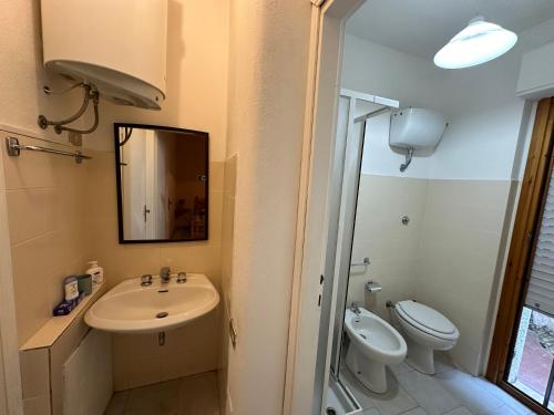a bathroom with a sink and a toilet and a mirror at Villaggio Malfidano in Buggerru
