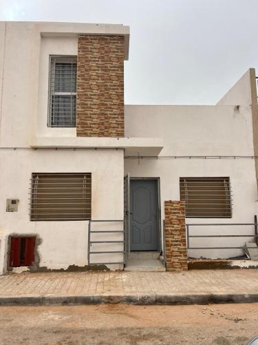 a white house with a blue door and two windows at Bait Khalij Dakhla 2 in Dakhla