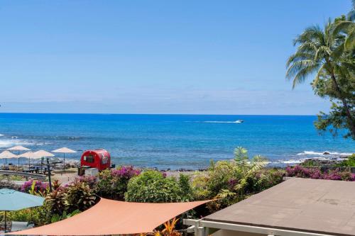 a view of the ocean with a red bus on the beach at Direct Oceanview Paradise in a luxury condo 2B2B,AC in Kailua-Kona
