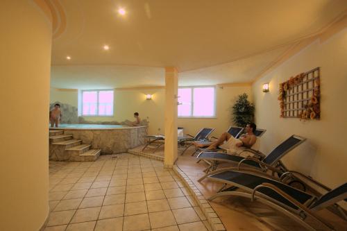 a group of people sitting in chairs in a room with a tub at Residence Montebel in Tesero