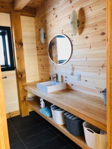 a bathroom with a sink and a mirror at Maison ULTIMA ÉCO in LʼIslet