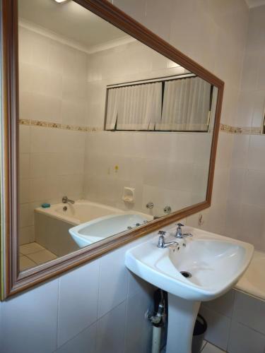 a bathroom with a sink and a mirror and a tub at Light House Lodge in Bela-Bela