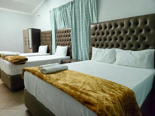a hotel room with two beds and a headboard at Light House Lodge in Bela-Bela