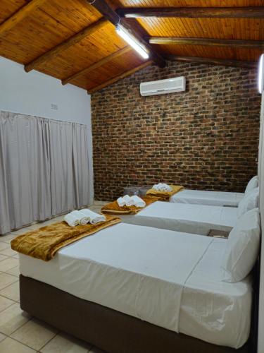 a bedroom with a large bed and a brick wall at Light House Lodge in Bela-Bela