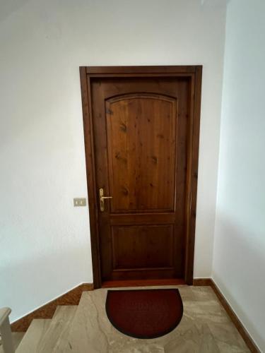 a wooden door in a room with a red rug at Appartamento Confortevole, Wi-Fi & Colazione Free in Lanusei