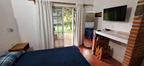 een slaapkamer met een bed, een tv en een raam bij Posada Meztitla in Tepoztlán