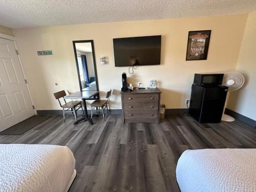 a room with a bedroom with a desk and a tv at Inn at the Sea in Long Beach
