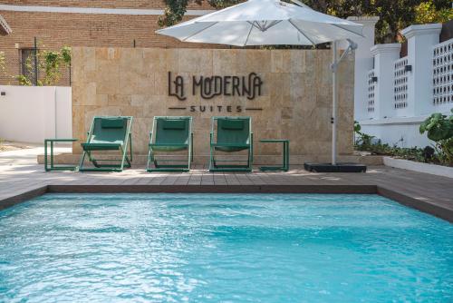 a swimming pool with two chairs and an umbrella at La Moderna Suites in Málaga
