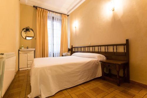 a bedroom with a large bed and a window at Pension Iberia in Llanes