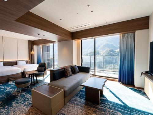 a hotel room with a couch and a bed at Beppu SUGINOI HOTEL in Beppu