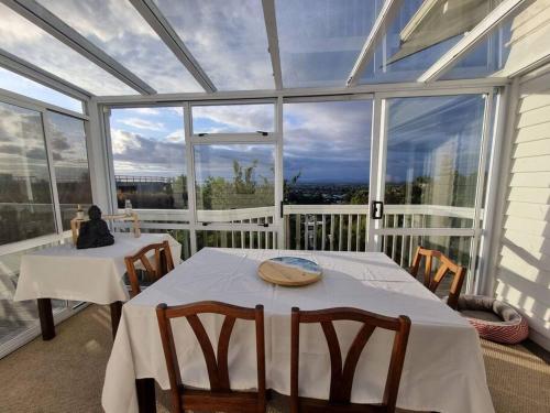 a conservatory with two tables and chairs and windows at Views on the Terrace in Napier