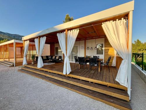 a house with a wooden deck with curtains at Ayana Mobile Home in Orebić