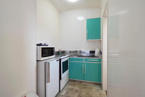 a kitchen with green cabinets and a white refrigerator at Mahoe Motel in Taumarunui