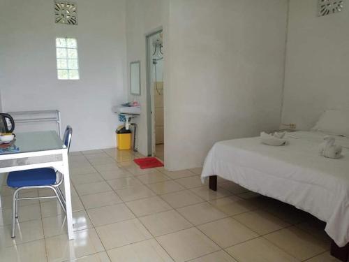 a white bedroom with a desk and a bed at Sao Ria Wisata Lodge in Kelimutu