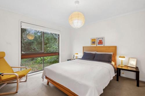 Un dormitorio con una cama y una silla y una ventana. en Darlana House - BYO Linen, en Anglesea