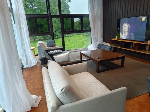 a living room with a white couch and a tv at Cómodo apartamento con piscina in Rivas