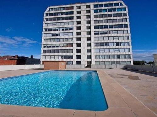 a building with a swimming pool in front of a building at Sensational St Kilda stay at Sunset Beach Tower in Melbourne