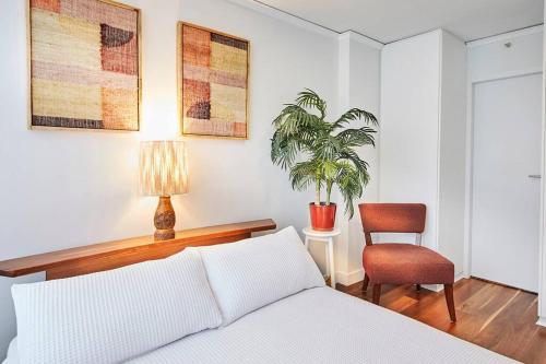 een slaapkamer met een bed en een stoel en een plant bij Sensational St Kilda stay at Sunset Beach Tower in Melbourne