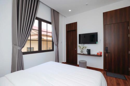 a bedroom with a white bed and a window at Camellia Villa Hotel in Khu Chi Lăng