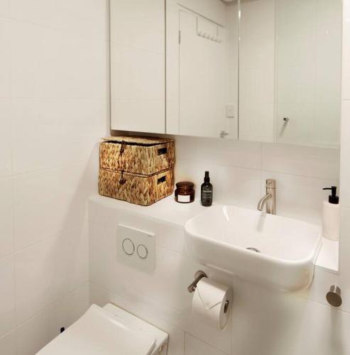 a white bathroom with a sink and a toilet at Sensational St Kilda stay at Sunset Beach Tower in Melbourne