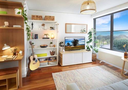 a living room with a flat screen tv and a guitar at Sensational St Kilda stay at Sunset Beach Tower in Melbourne