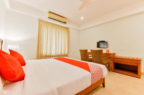 a bedroom with a bed and a desk and a television at Super Townhouse Vembanad Tourist Home in Cochin