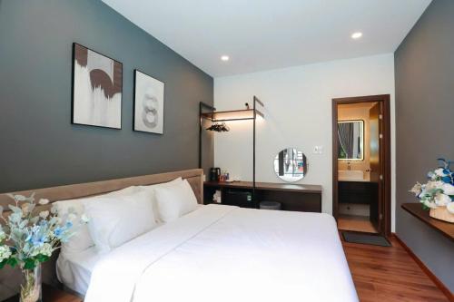 a bedroom with a large white bed and a mirror at Camellia Villa Hotel in Khu Chi Lăng