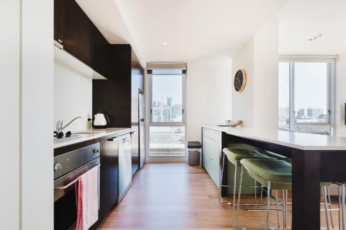 a kitchen with a counter and some chairs in it at Easy Eastside - Urban Chic with a Rooftop Pool Oasis in Melbourne