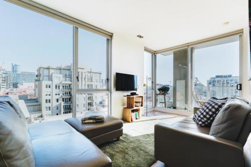 a living room with a couch and large windows at Easy Eastside - Urban Chic with a Rooftop Pool Oasis in Melbourne