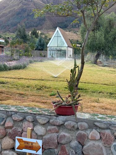 a sign on a stone wall with a tree and a building at Hotel Boutique La Caballeriza in Quillacollo