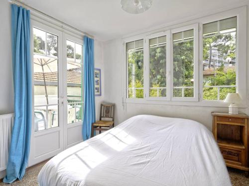 - une chambre avec un lit doté de rideaux bleus et de fenêtres dans l'établissement Arcachon : Appartement T4 avec terrasse et parking à 400m de la plage ! - FR-1-433-128, à Arcachon