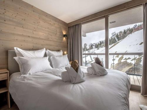 una camera da letto con un letto bianco con due bambole sedute sopra di Superbe appart 96m² - 8 pers - Centre station - Proche pistes - SPA, Wifi, Parking - FR-1-631-206 a Courchevel
