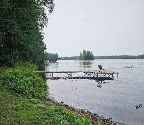 a bench sitting on a dock in the middle of a lake at Butler's Bay Cottage cottage in Hayward