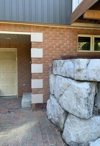 a brick building with a stone wall next to a garage at Cozy 1 bedroom basement apartment 14 days minimum in Fonthill