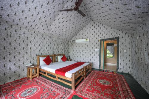 a bedroom with a bed with red pillows on it at Corbett Nature Retreat in Rāmnagar