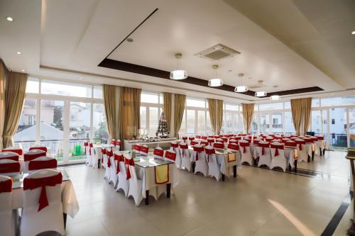 una sala banchetti con tavoli e sedie rossi e bianchi di Thanh Lich Hue Hotel a Hue