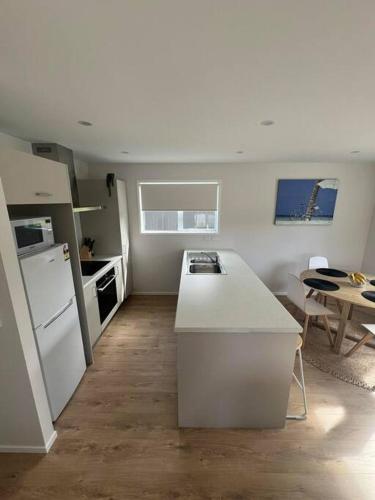 a kitchen with a white counter top and a table at Bach At 45 in Ahipara