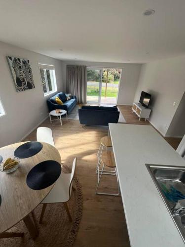 a kitchen and living room with a table and chairs at Bach At 45 in Ahipara
