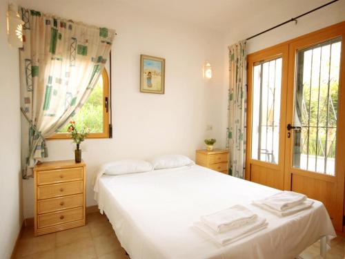 a bedroom with a white bed and a window at Villa Marycar in Jávea